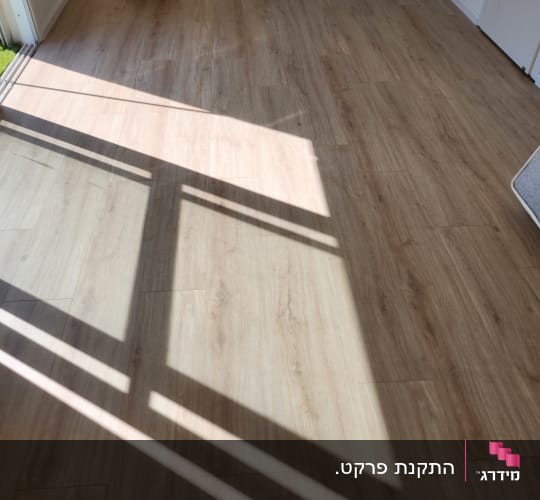 רצפת פרקט עץ בהירה עם צללים מחלון